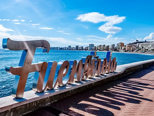 Schriftzug "Fuengirola" am Meer, sonnig.